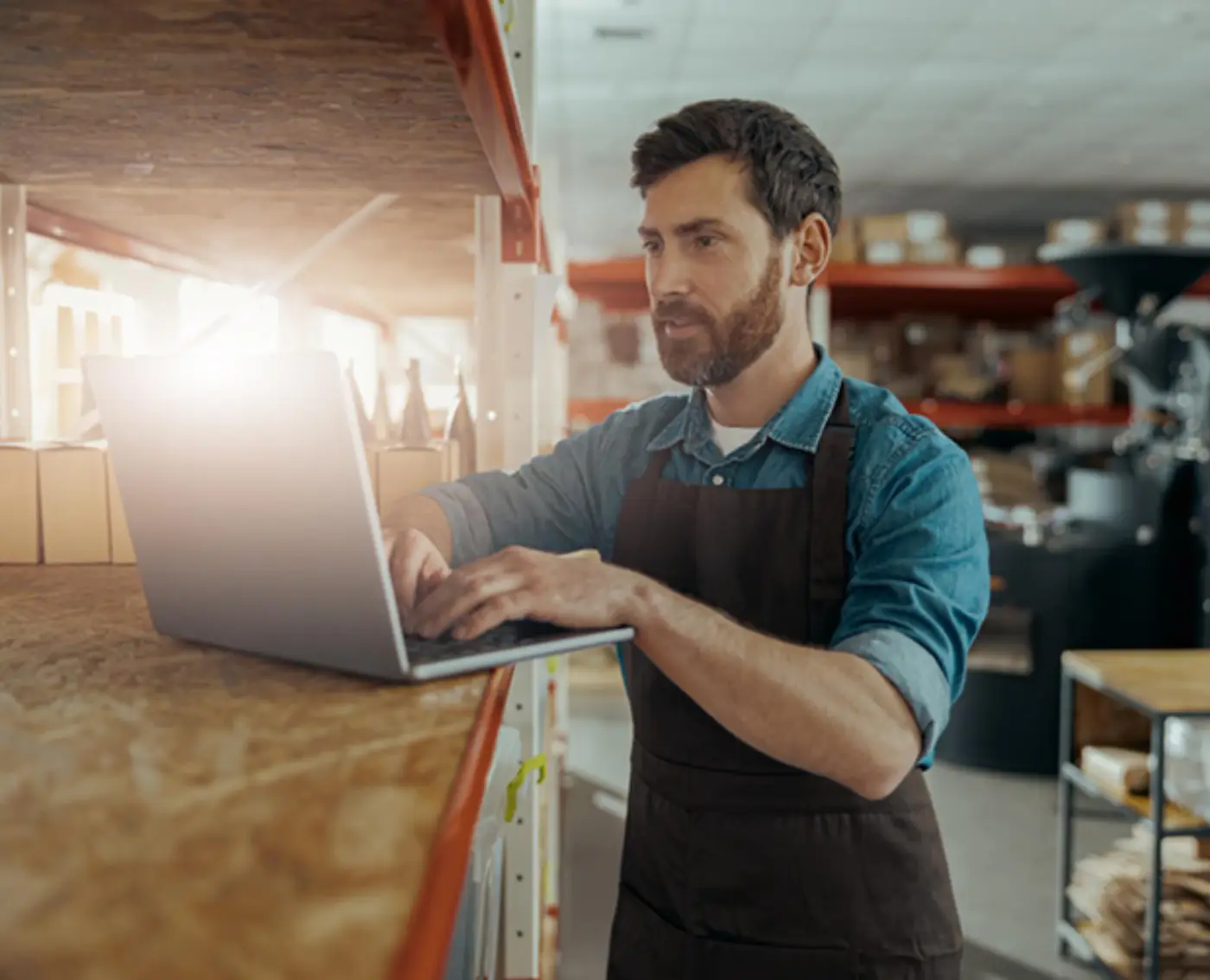 Shop worker checking stock on a laptop in a store room